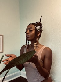 a woman holding a plant in front of a wall